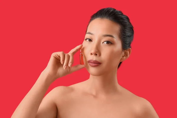 赤い背景にアンプルを持つ美しいアジアの女性 スキンケアコンセプト — ストック写真