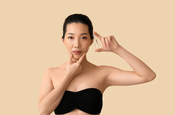 ベージュの背景にアンプルを持つ美しいアジアの女性 スキンケアコンセプト — ストック写真