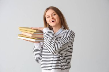 Gri arkaplan üzerine kitap yığını olan mutlu kız öğrenci