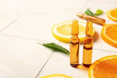 C vitamini ve beyaz fayans zemininde farklı narenciye dilimleri olan ampuller.