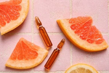 C vitamini ve pembe fayanslı farklı turunçgil dilimli ampuller.