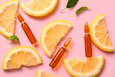 C vitamini ve pembe arka planda limon dilimleri olan ampuller