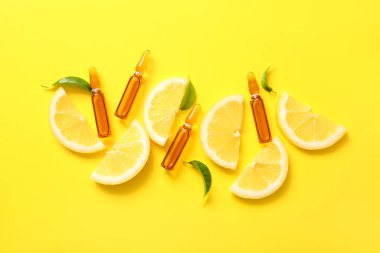 Sarı zemin üzerinde C vitamini ve limon dilimleri olan ampuller