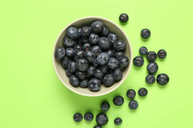 Yeşil arka planda taze yaban mersinli kase