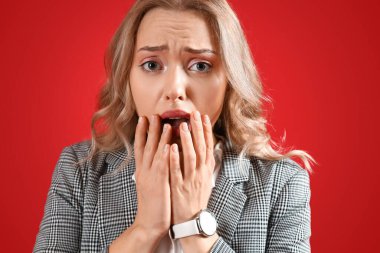 Kırmızı arka planda panik atak geçiren genç bir kadın.