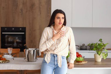 Genç bir kadın mutfakta panik atak geçiriyor.