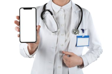 Steteskoplu kadın doktor beyaz arka planda izole edilmiş bir cep telefonu ekranı gösteriyor