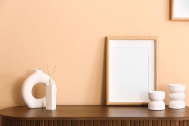 Odadaki bej duvarın yanındaki masada bir şişe sazlık ayırıcı ve boş çerçeve.