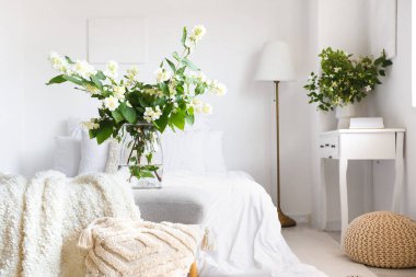 İçinde yasemin çiçekleri olan vazo, yatak odasının iç tarafındaki bankta.