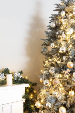 Parlayan ışıkları olan Noel ağacı, şöminenin yanında altın ve gümüş toplar.