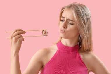 Pembe arka planda lezzetli suşisi olan düşünceli genç bayan, yakın plan.
