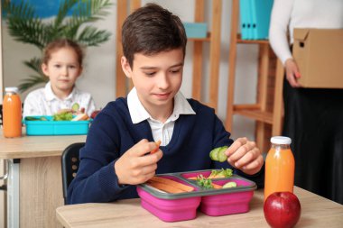 Küçük çocuk öğle yemeğini sınıfta yiyor.