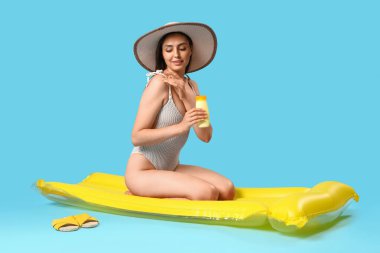 Güneş kremi ve mavi arka planda şişirilebilir şiltesi olan genç bir kadın.