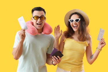 Pasaportları ve sarı arka planda biletleri olan genç çift.
