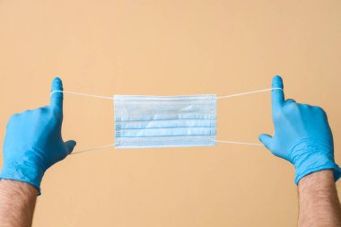 Bej arka planda tıbbi maskeli bir doktor.