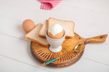 Haşlanmış tavuk yumurtası ve beyaz ahşap arka planda ekmek tutacağı.