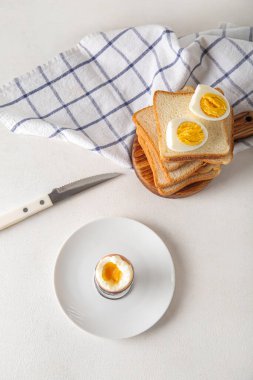 Beyaz arka planda haşlanmış tavuk yumurtası ve ekmek tutacağı.