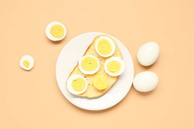 Turuncu arka planda haşlanmış yumurtalı tost.