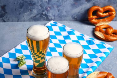 Bavyera bayrağı, biralı kupalar ve mavi arka planda krakerler.