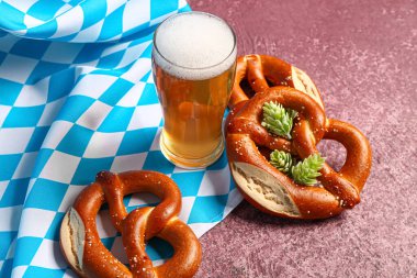 Bavyera bayrağı, biralı bardak ve mor arka planda kraker.