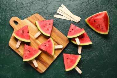 Yeşil arka planda tatlı karpuz çubukları olan ahşap tahta.