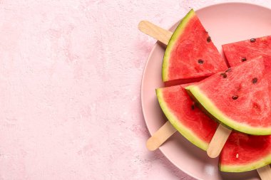 Pembe arka planda tatlı karpuz çubukları olan bir tabak.