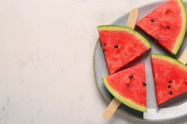 Beyaz arka planda tatlı karpuz çubukları olan bir tabak.