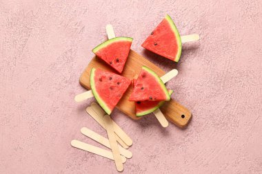 Pembe arka planda tatlı karpuz çubukları olan ahşap tahta tahta.
