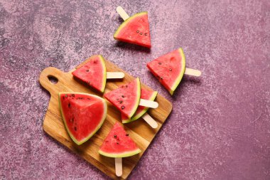 Mor zemin üzerinde tatlı karpuz çubukları olan ahşap tahta tahta.