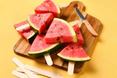 Sarı arka planda tatlı karpuz çubukları olan ahşap tahta.