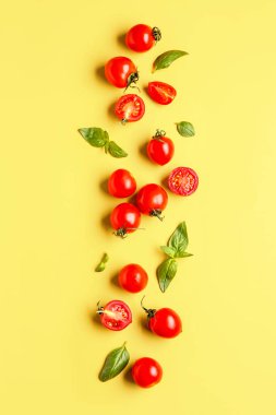 Taze vişneli domates ve sarı arka planda fesleğen.