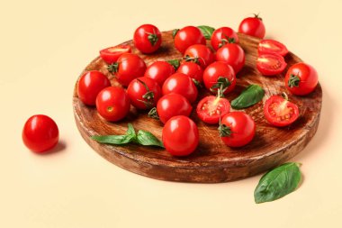 Taze kiraz domatesli ahşap tahta ve turuncu arka planda fesleğen.