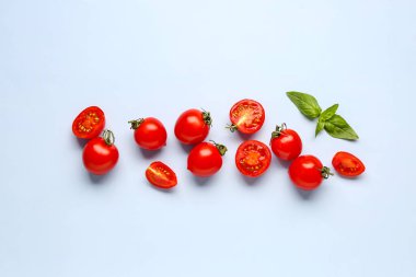 Taze vişneli domates ve mavi arka planda fesleğen.