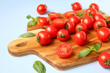 Taze kiraz domatesli ahşap tahta ve mavi arka planda fesleğen.