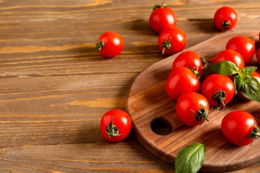 Taze vişneli domates ve ahşap masada fesleğen.