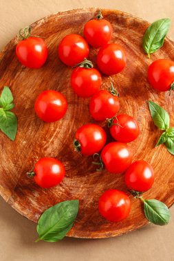 Taze kiraz domatesli ahşap masa ve kahverengi masada fesleğen.