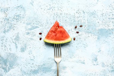 Taze karpuz parçalı çatal ve mavi arka planda tohumlar.