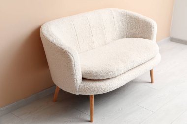 Bej duvarın yanındaki rahat beyaz kanepe.