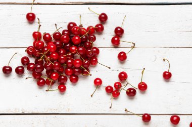 Beyaz ahşap arka planda kırmızı kiraz yığını