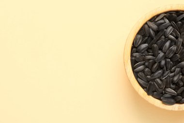 Bej arkaplanda ayçiçeği tohumları olan bir kase