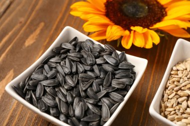 Tahta arka planda ayçiçeği tohumları olan kaseler.
