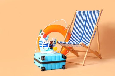 Çantası, şamandırası ve bej arka planda plaj aksesuarları olan bir iskemle. Seyahat kavramı