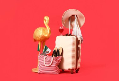 Kırmızı arka planda farklı plaj aksesuarları olan bavul. Seyahat kavramı