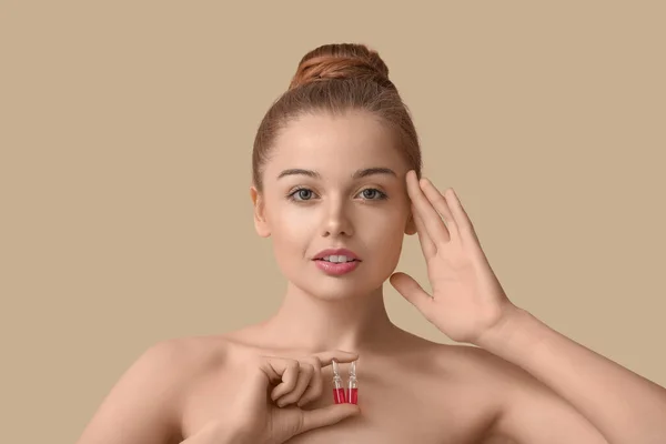 ベージュの背景にアンプルを持つ美しい若い女性 スキンケアコンセプト — ストック写真