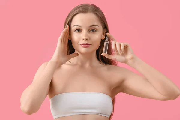 ピンクの背景にアンプルを持つ美しい若い女性 スキンケアコンセプト — ストック写真