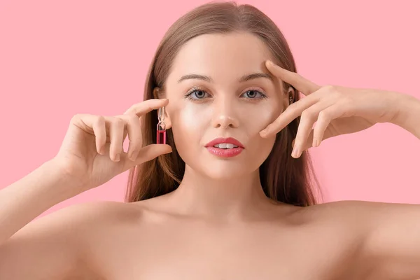 ピンクの背景にアンプルを持つ美しい若い女性 スキンケアコンセプト — ストック写真
