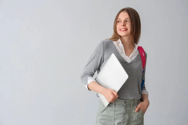 带着灰色背景背包和笔记本电脑的快乐女生 — 图库照片