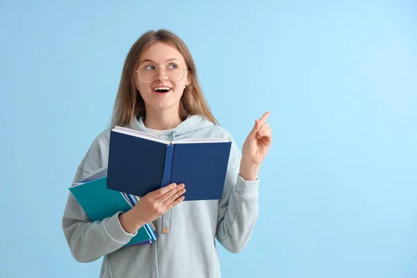 Ευτυχισμένη Μαθήτρια Διαφορετικά Βιβλία Που Δείχνει Κάτι Στο Μπλε Φόντο — Φωτογραφία Αρχείου
