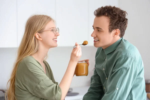 Young Woman Feeding Her Boyfriend Tasty Nut Butter Kitchen — Stock Photo, Image