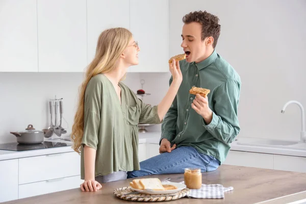 Young Woman Feeding Her Boyfriend Tasty Toast Nut Butter Kitchen — Stock Photo, Image